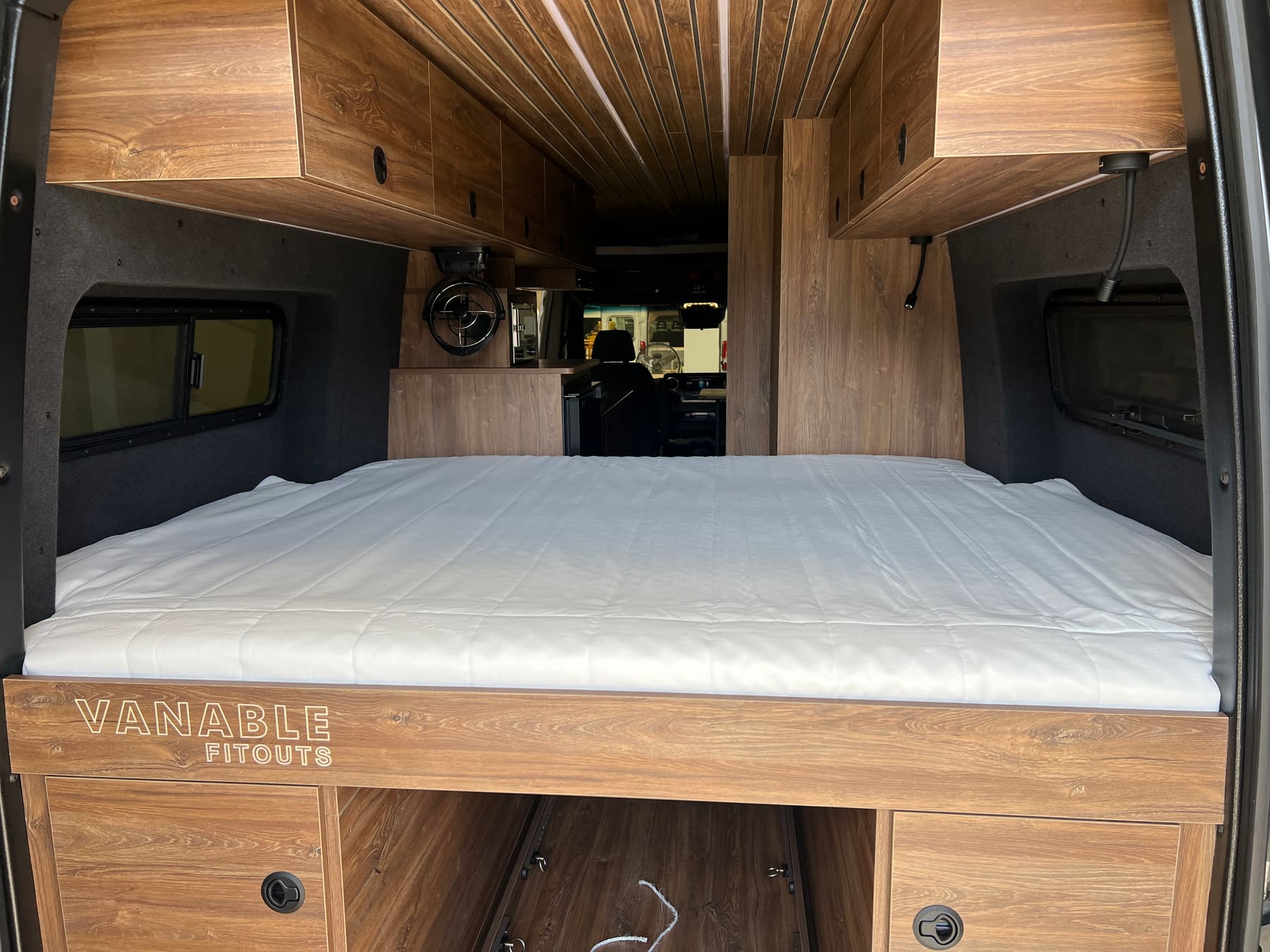 A campervan fit-out with the bed made up across the rear