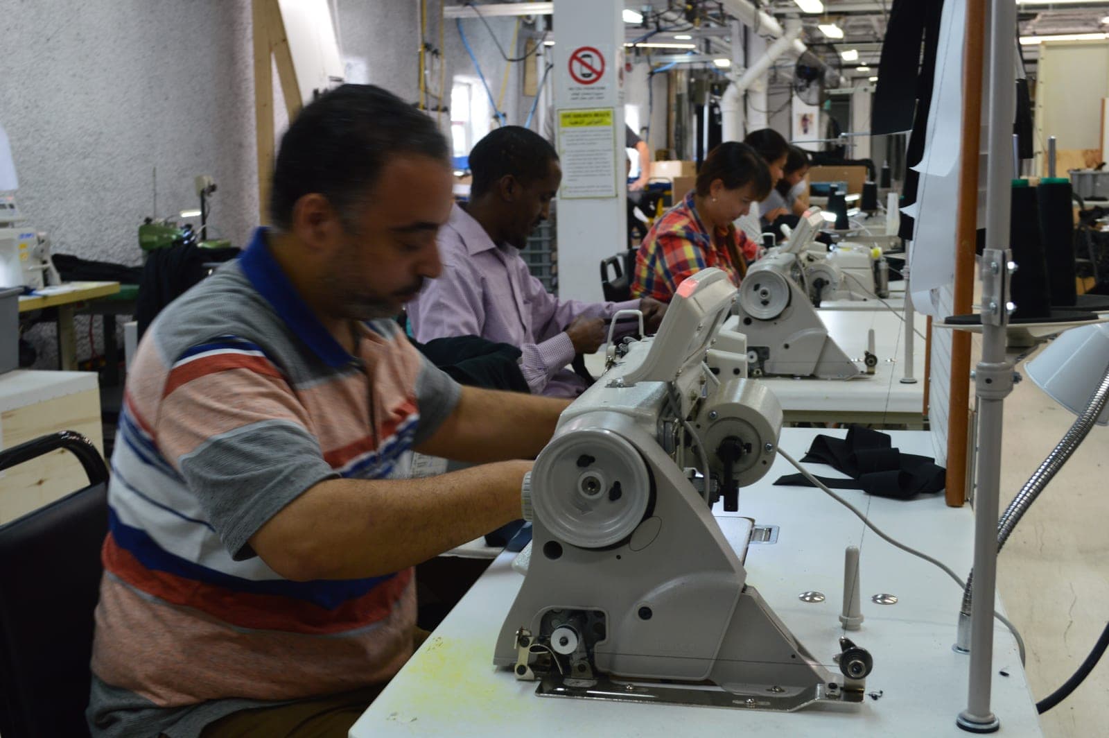A machinist guiding a garment through an industrial sewing machine