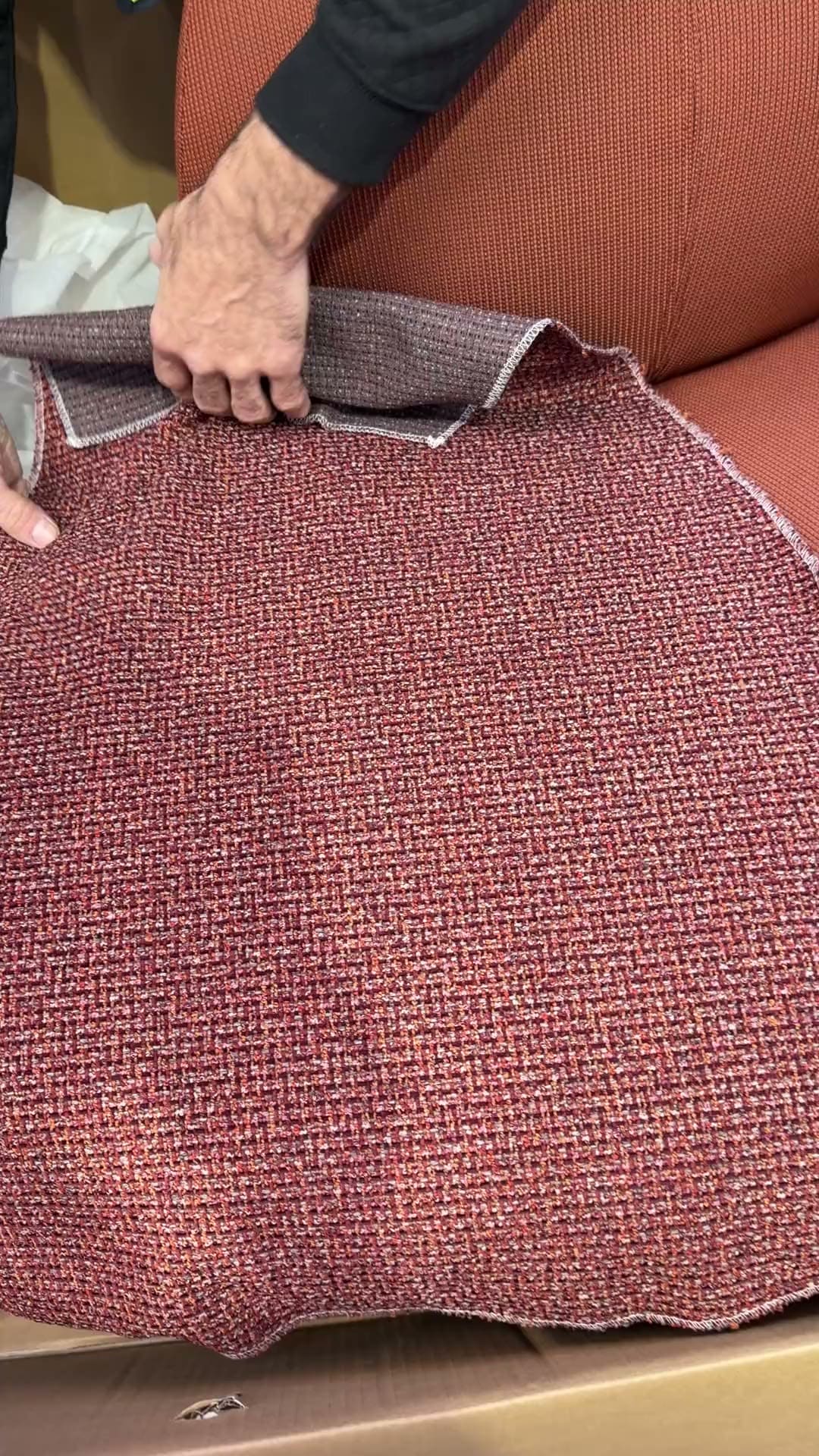 Hands fitting a knit cover over a seat shell in the workroom