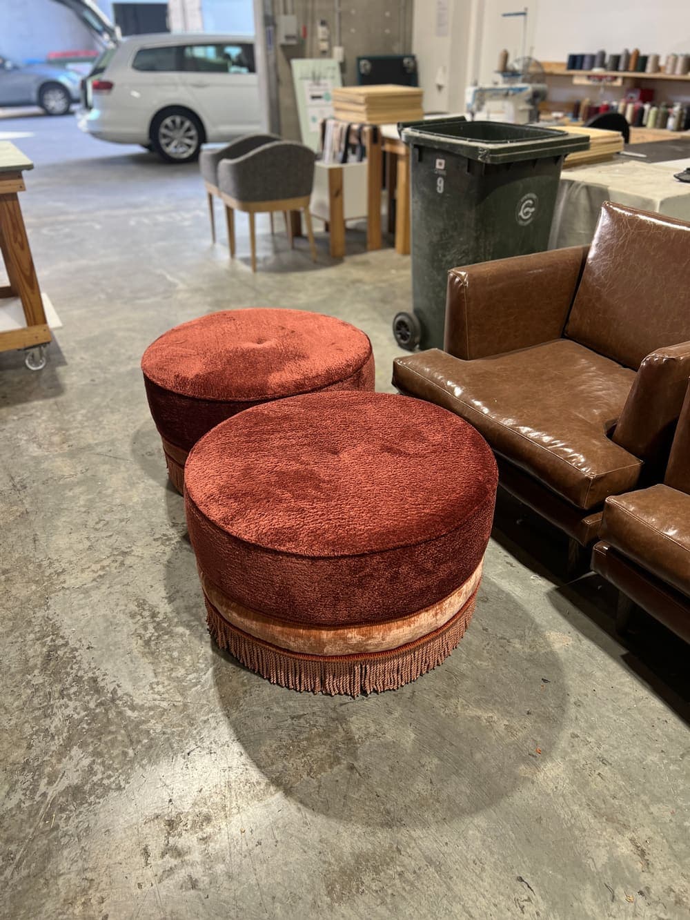 Fringed velvet ottomans beside a leather armchair